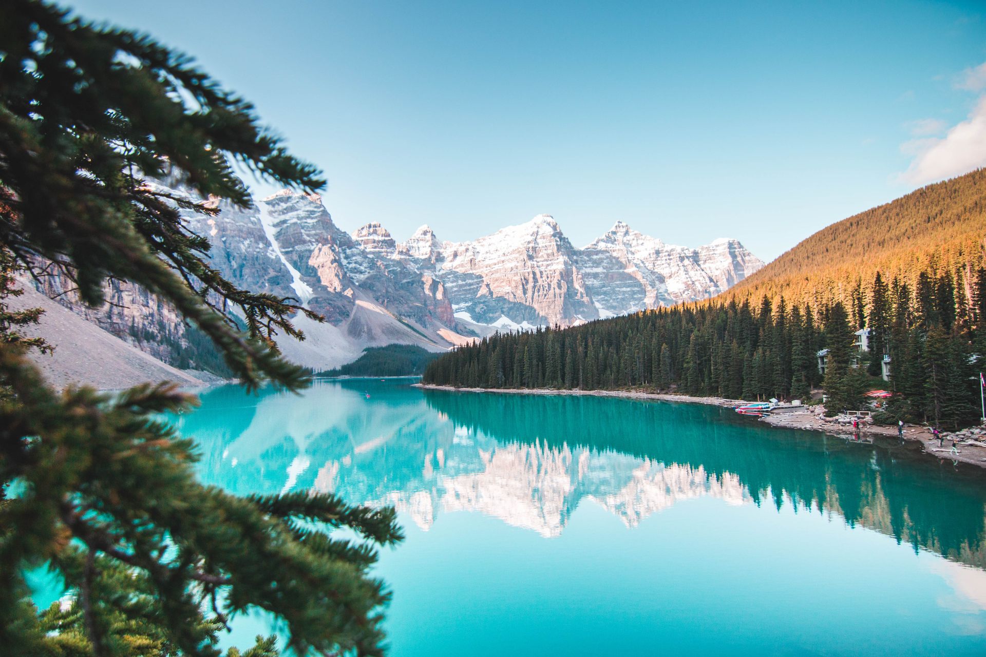 Clear alpine lake reflecting snow-capped peaks under an open blue sky